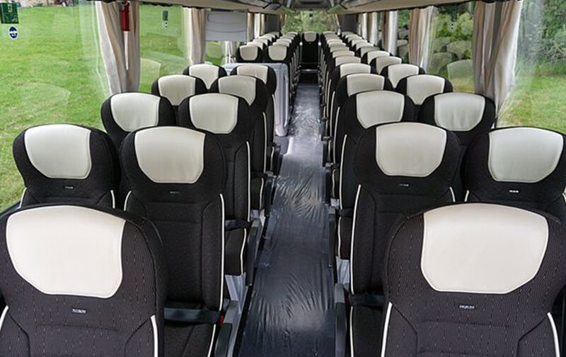 Interno di un pullman con sedili reclinabili e corridoio centrale